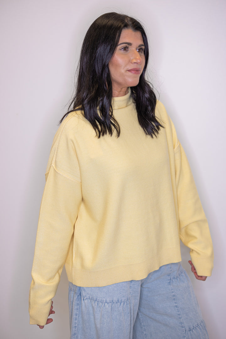 Women's butter yellow knit mock neck top showing drop shoulder