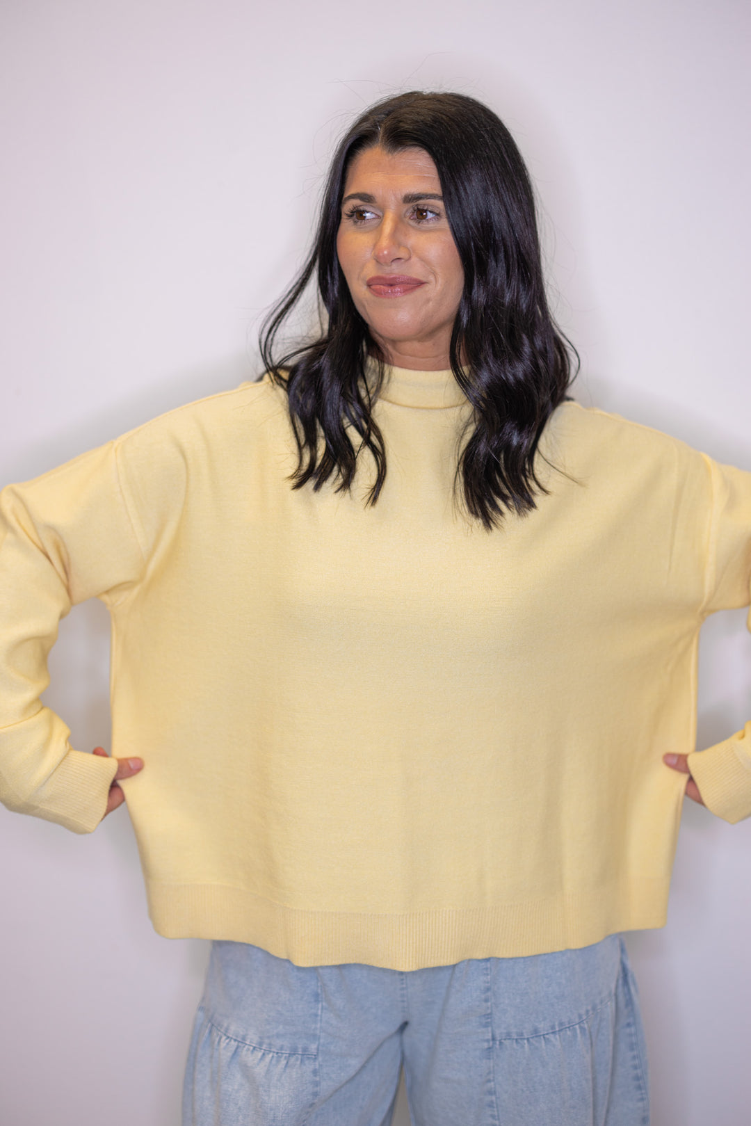 Women's butter yellow knit mock neck top showing semi-cropped length