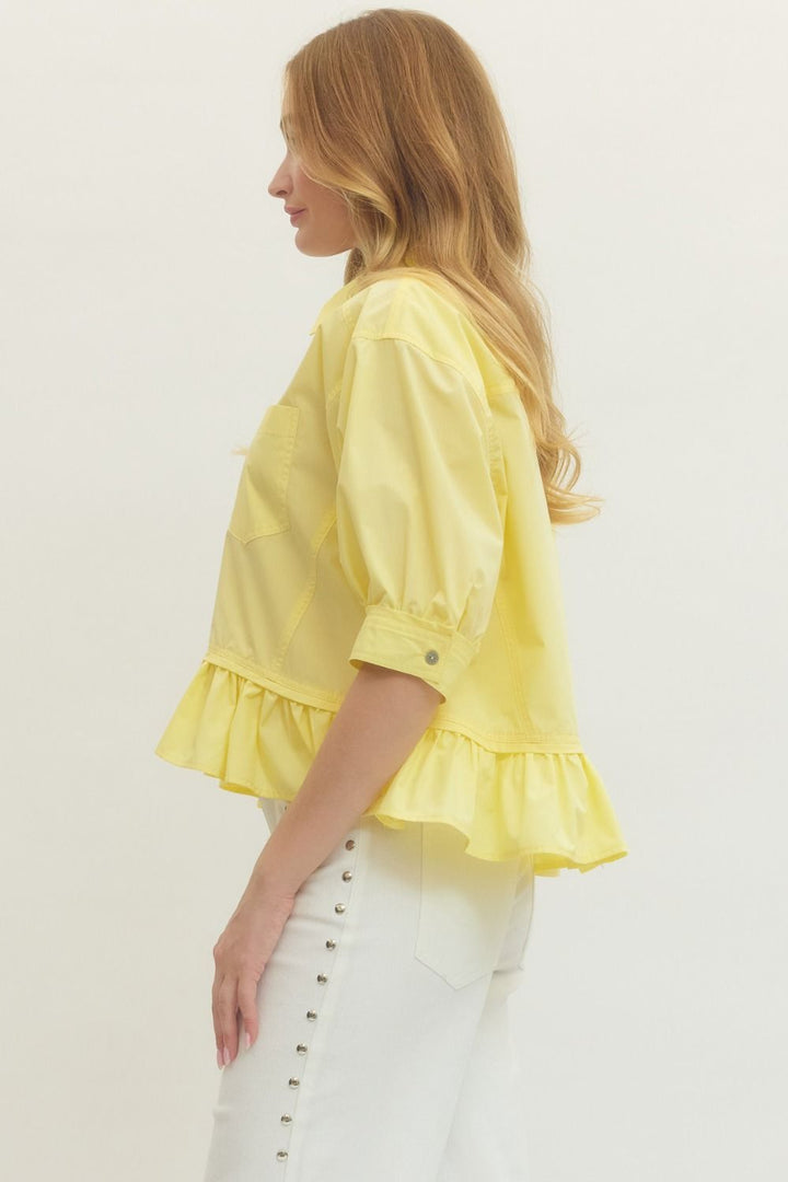 Women's semi-cropped button down yellow peplum top with ruffled hem by Entro showing side view